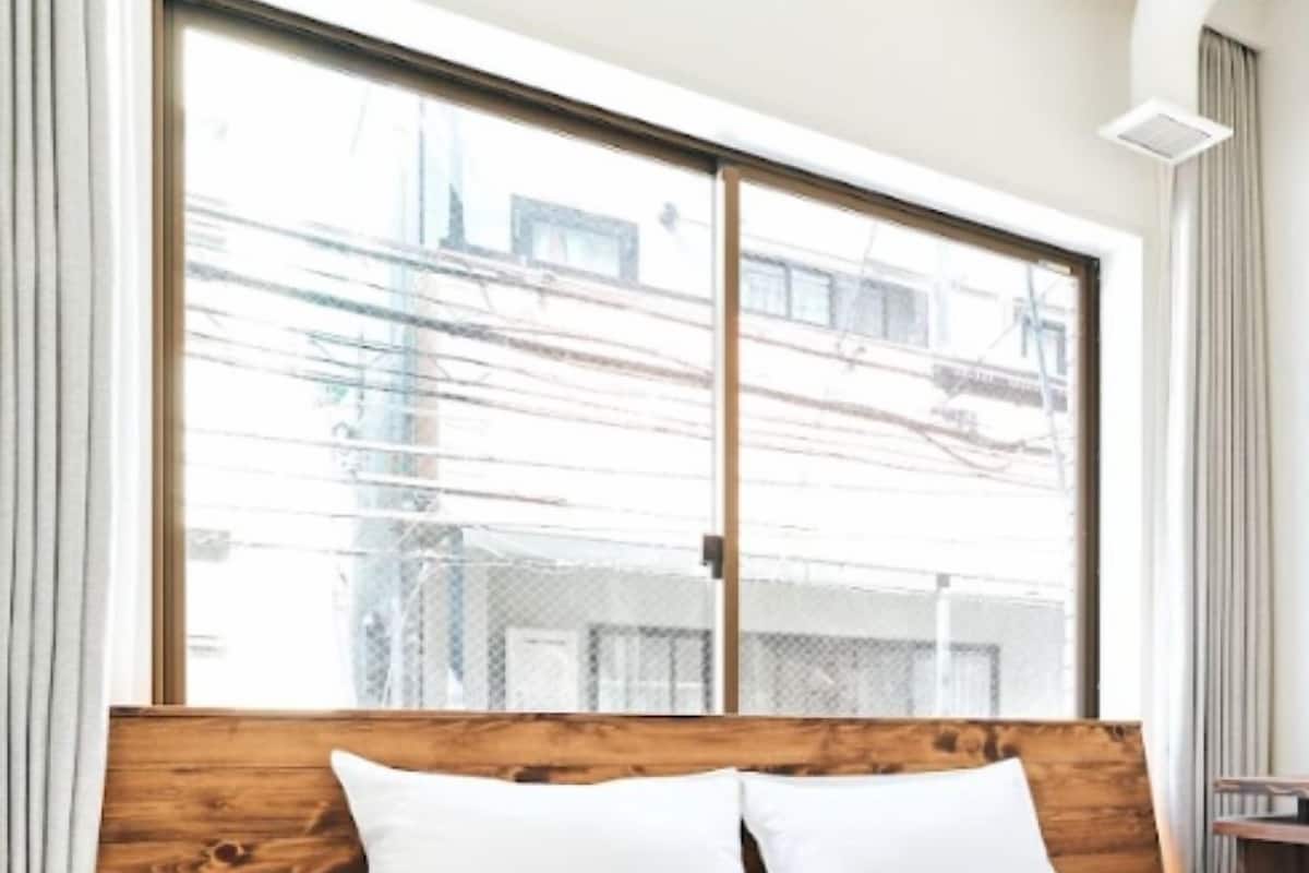 Una habitación de hotel con un amplio ventanal, cabecera de madera y una cama bien tendida.