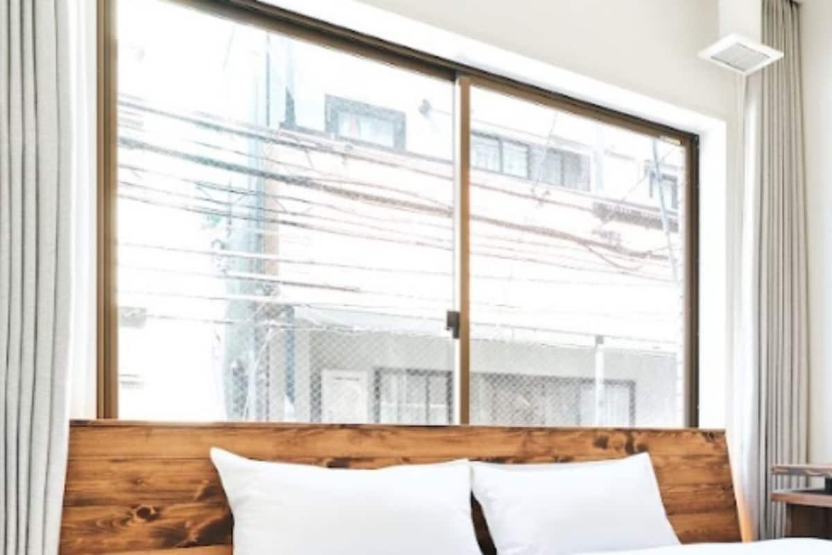 A hotel room with a large window, a wooden headboard, and a neatly made bed.