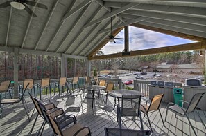 A covered outdoor seating area with tables and chairs, a ceiling fan, and a view of a parking lot and trees. - Lake Keowee Resort Condo w/ Fantastic View (Salem)