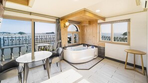 A balcony with a hot tub, a table, and chairs. - Daebudo Geugotegamyeon Pension (Ansan)