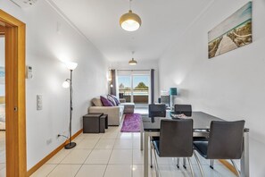 Un salon moderne avec un canapé, une table à manger, des chaises et une vue sur l’extérieur.
