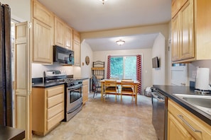 Kitchen features a central island, microwave, sink, and dining table with chairs.