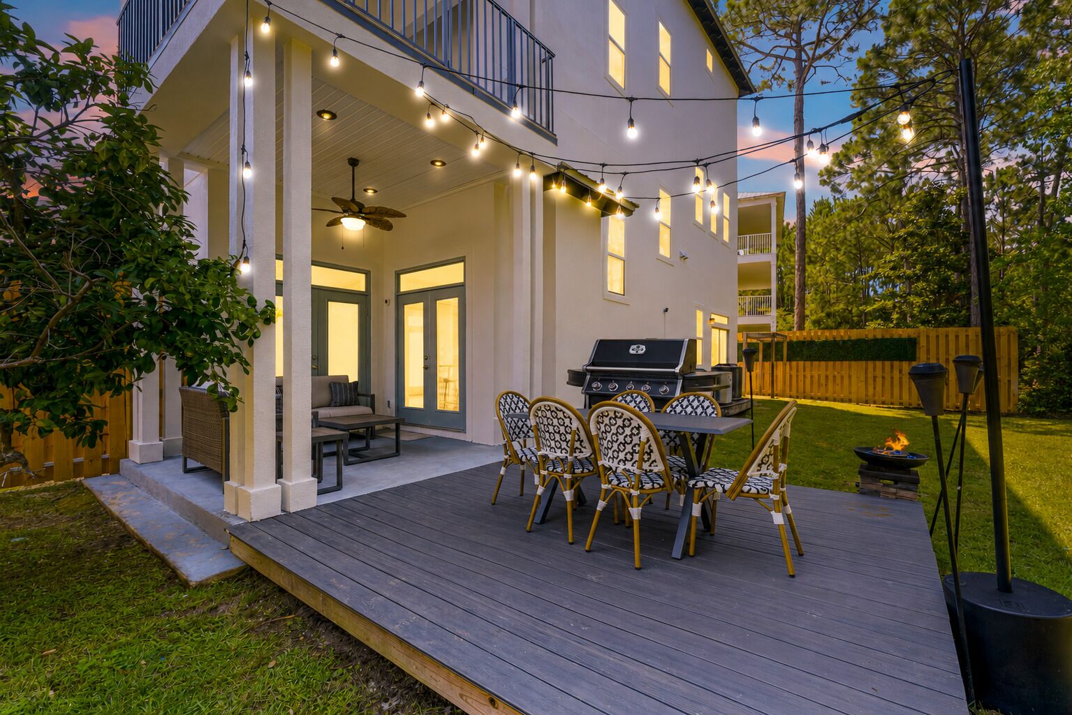 A deck with outdoor furniture, a grill, and string lights.