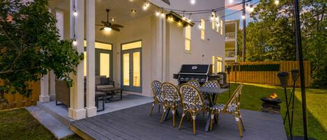 A deck with outdoor furniture, a grill, and string lights.