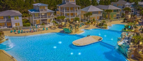 A resort with multiple swimming pools, a beach area, and a variety of buildings.