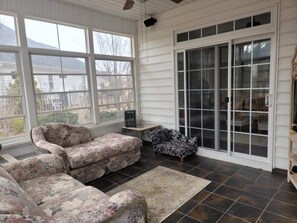 Relax in this serene sunroom with a sofa, armchair, and decorative table.