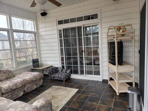 Relax in this sunroom with a high ceiling, ceiling fan, and large sliding glass door leading to an outdoor area.