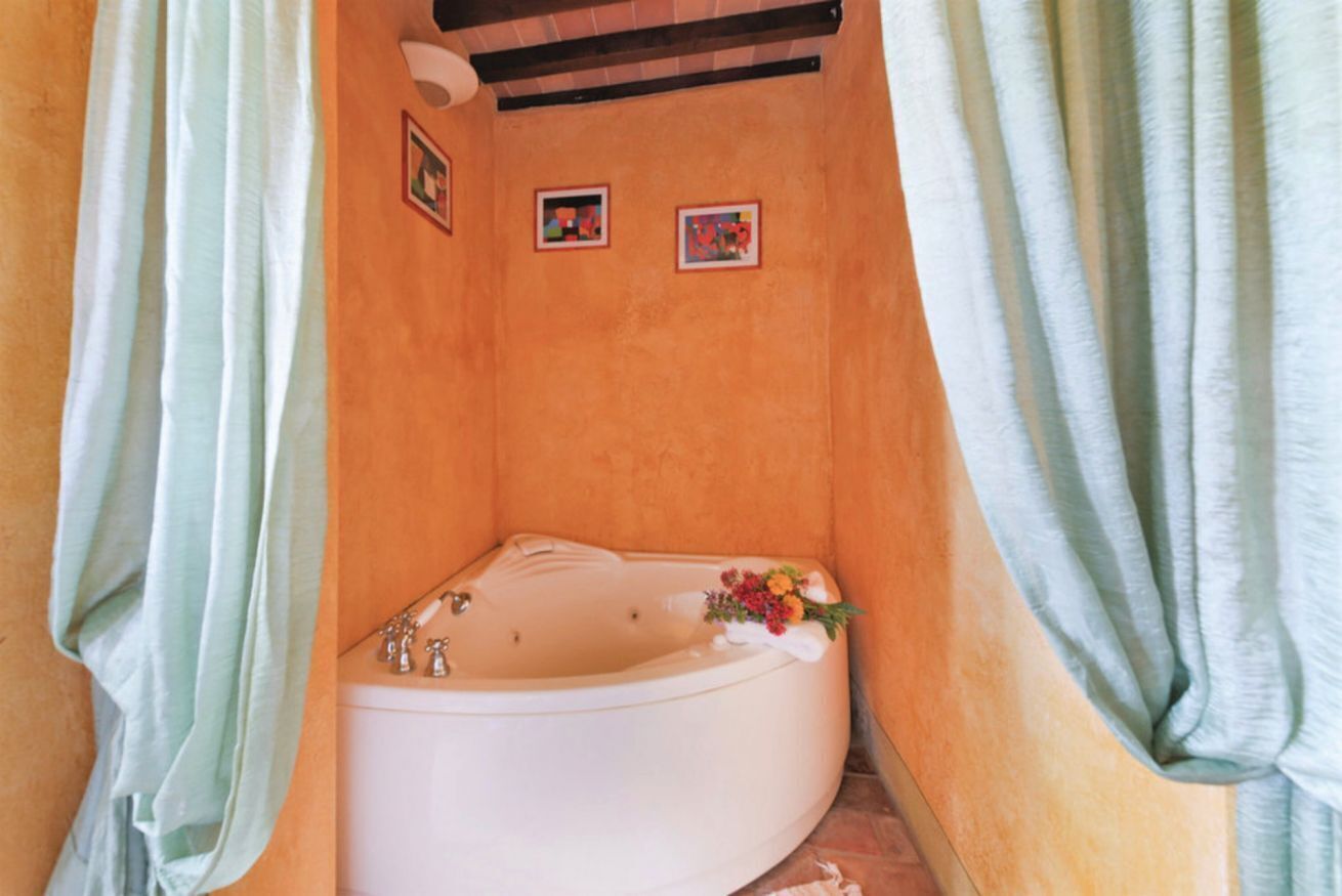A bathroom with a bathtub, two framed pictures on the wall, and a shower curtain.