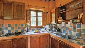 A kitchen with wooden cabinets, a tiled backsplash, a gas stove, a coffee maker, and a sink.
