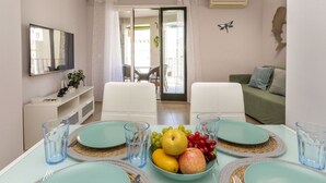 A dining area with a table set for four, a fruit bowl, and a view of the balcony. - Lovely apartment for 4 guests with WIFI, A/C, TV and balcony (Tossa De Mar)