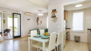 A modern kitchen with a dining area, featuring a table set for four, a refrigerator, and a window. - Lovely apartment for 4 guests with WIFI, A/C, TV and balcony (Tossa De Mar)