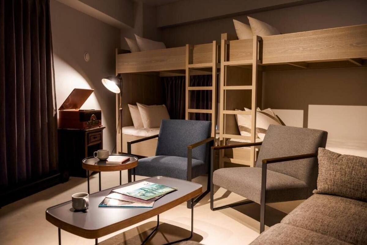 A cozy room with a bunk bed, a desk with a lamp, and two armchairs.