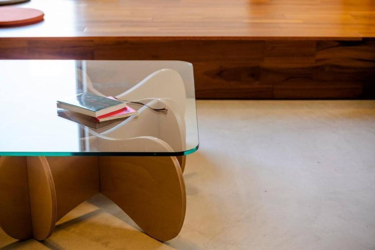 A modern table with a glass top and wooden legs.