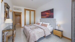 Une chambre d’hôtel moderne avec un grand lit, une table de chevet, un miroir et un tableau au mur.