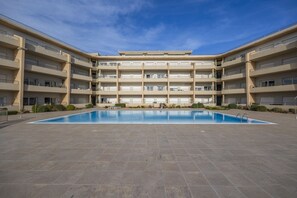 Un immeuble résidentiel à plusieurs étages doté d’une piscine centrale.
