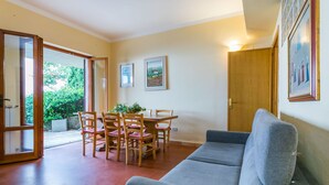 A living room with a grey sofa, wooden dining table with chairs, and a door leading to a balcony. - Beautiful apartment for 4 guests with WIFI, pool, terrace, pets allowed and panoramic view (Lamporecchio)
