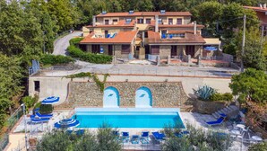 A pool area with blue lounge chairs and a stone wall. - Beautiful apartment for 4 guests with WIFI, pool, terrace, pets allowed and panoramic view (Lamporecchio)