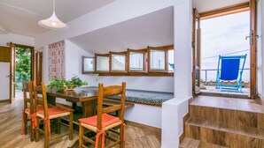 A dining area with a wooden table and chairs, a bench, and a view of the outside through large windows. - Lovely apartment for 4 guests with pool, WIFI, balcony, pets allowed and panoramic view (Lamporecchio)