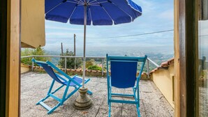 A balcony with two blue chairs, a blue umbrella, and a view of a cityscape. - Lovely apartment for 4 guests with pool, WIFI, balcony, pets allowed and panoramic view (Lamporecchio)