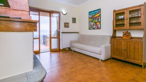 A living room with a white sofa, wooden cabinet, and a painting on the wall. - Lovely apartment for 2 guests with WIFI, pool, terrace and pets allowed (Lamporecchio)
