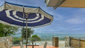 A patio with a table and chairs under a striped umbrella, overlooking a scenic view. - Lovely apartment for 2 guests with WIFI, pool, terrace and pets allowed (Lamporecchio)