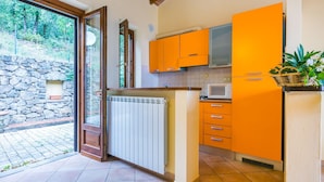 A kitchen with orange cabinets, a white radiator, and a stone wall outside. - Beautiful apartment for 2 guests with pool, WIFI, terrace, pets allowed and panoramic view (Lamporecchio)