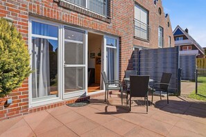 Une maison en briques avec un patio, des meubles d’extérieur et une porte-fenêtre coulissante.