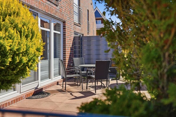 A patio with outdoor furniture, a brick building, and a tree.
