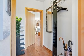 A hallway with a wooden door, a mirror, a coat rack, and a plant.