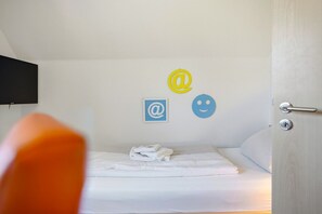 Une chambre d’hôtel avec un lit, un téléviseur fixé au mur et une porte dotée d’une poignée.