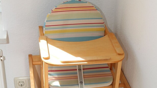A wooden bunk bed with striped bedding in a corner of a room.