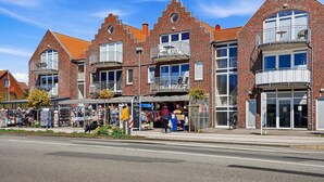 A multi-story brick building with balconies, storefronts, and a clear sky.