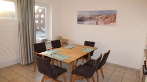 A dining area with a wooden table, six chairs, and a painting on the wall.