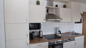 A modern kitchen with white cabinets, a microwave, a toaster, a coffee maker, and a stove.