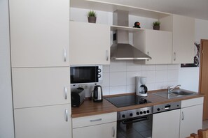 A modern kitchen with white cabinets, a microwave, a toaster, a coffee maker, and a stove.