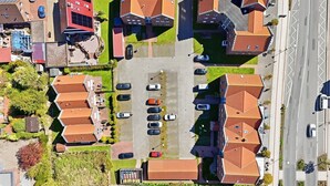 An aerial view of a residential area with multiple houses, a parking lot, and a road.