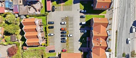 An aerial view of a residential area with multiple houses, a parking lot, and a road.