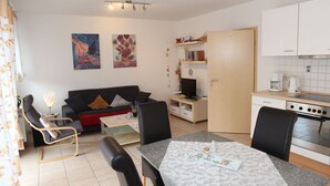 Ein modernes Wohnzimmer mit einer Couch, Sesseln, einem Couchtisch und Kunstwerken an den Wänden.