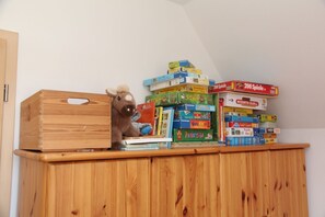 Un meuble en bois contenant un animal en peluche et divers jeux de société.