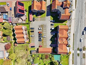 Eine Vogelperspektive auf ein Wohngebiet mit mehreren Häusern, einem Parkplatz und einer Straße.