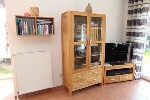 Un salon comprenant un meuble en bois, une bibliothèque, un radiateur et un téléviseur.