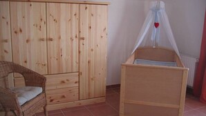 A room with a wooden wardrobe, a wicker chair, and a wooden bed with a canopy.
