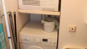 A laundry room with a top-loading washing machine and a front-loading dryer stacked on top.