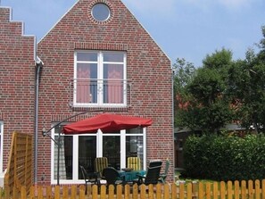 Ein Ziegelhaus mit rotem Markisenüberhang, einer mit Vorhängen versehenen Fenster und einem Holzzaun.