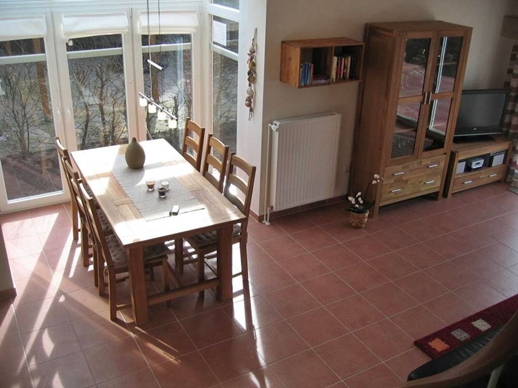 Un comedor con una mesa y sillas, un mueble con televisor y un radiador.