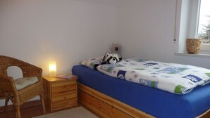 Ein Schlafzimmer mit einem Einzelbett, einem Nachttisch, einem Stuhl und einem Fenster mit Blick.