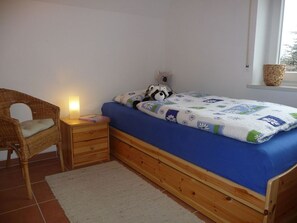 Ein Schlafzimmer mit einem Einzelbett, einem Nachttisch, einem Stuhl und einem Fenster mit Blick.