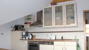 A kitchen with white cabinets, a microwave, a toaster, a coffee maker, and a dishwasher. - Juistblick - Beautiful top floor apartment (60sqm) for 4 persons with balcony and (Norden)