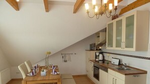 A kitchen with wooden cabinets, a sink, and a dining area with a table and chairs. - Juistblick - Beautiful top floor apartment (60sqm) for 4 persons with balcony and (Norden)