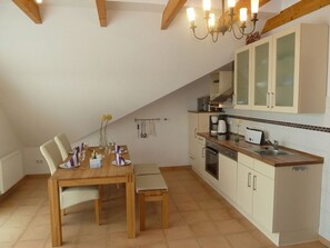 Une cuisine avec des meubles de rangement en bois, un évier et un coin repas comprenant une table et des chaises.